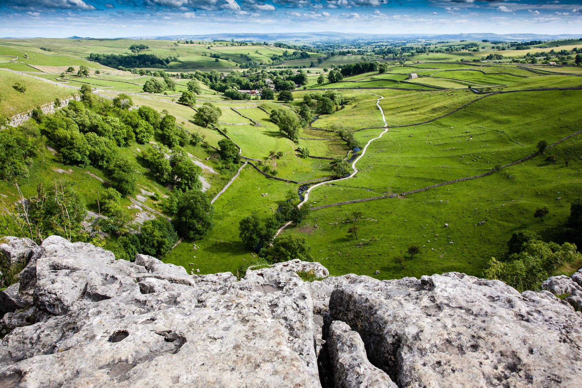 View from the top of Malham Cove showing lush green fields stretched to the horizon